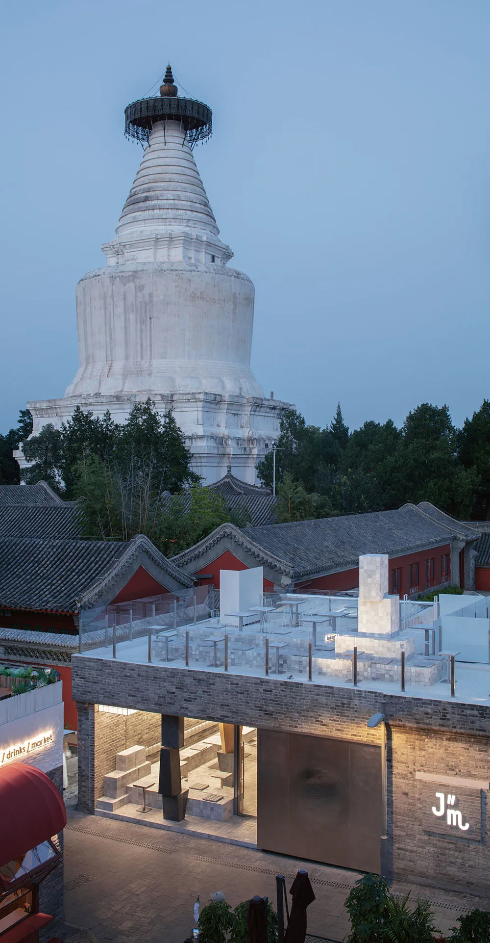 夜間的白色混凝土佛塔，周圍有樹木與傳統中式建築。