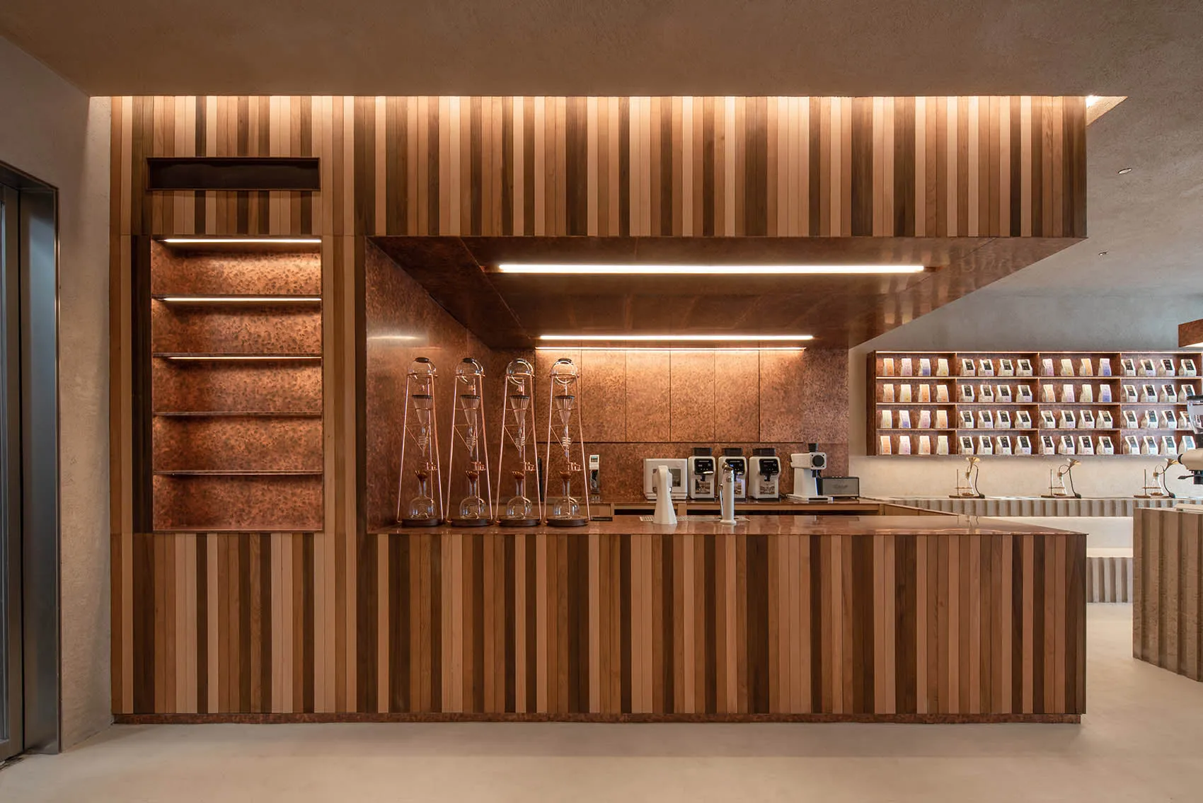 A modern, industrial-style coffee shop counter made of wood, featuring a striped design and various coffee-making equipment.