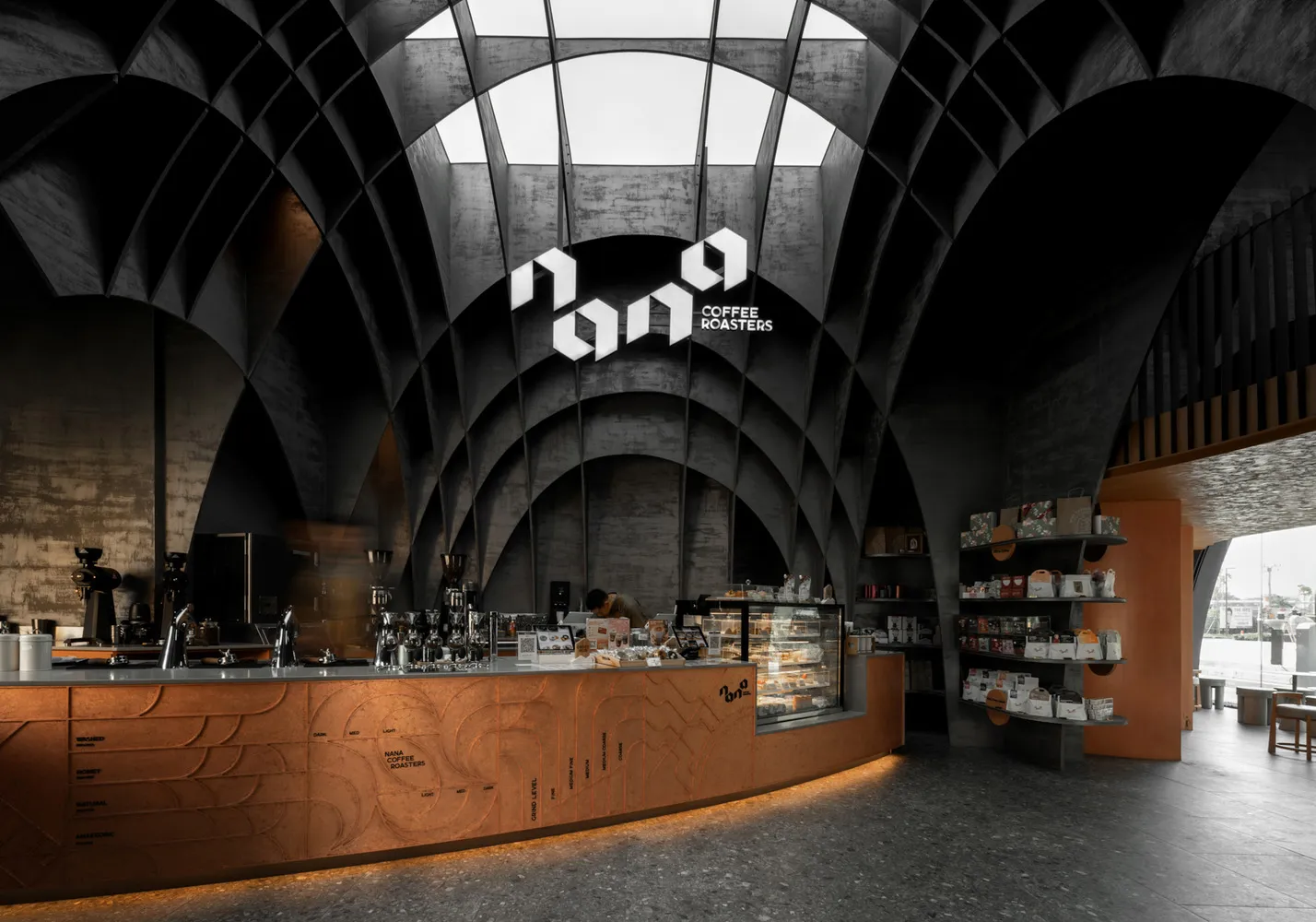 一間現代工業風咖啡店,設有混凝土吧台,台面下方有咖啡烘焙品牌標誌。