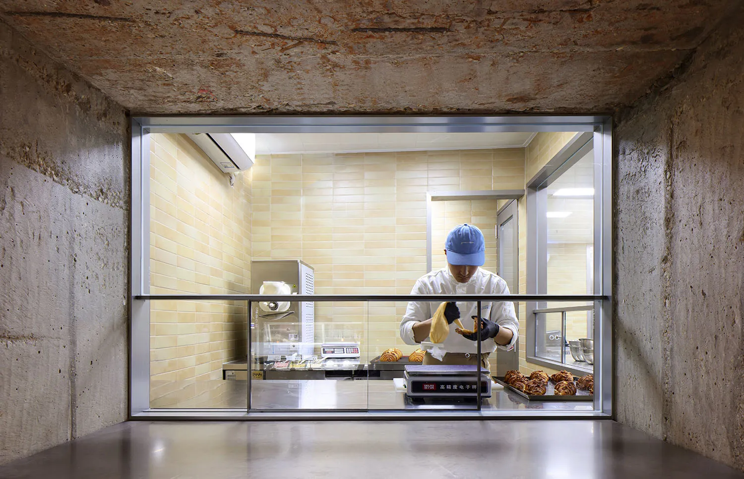 A person wearing gloves cleans a pastry in a concrete bakery kitchen.