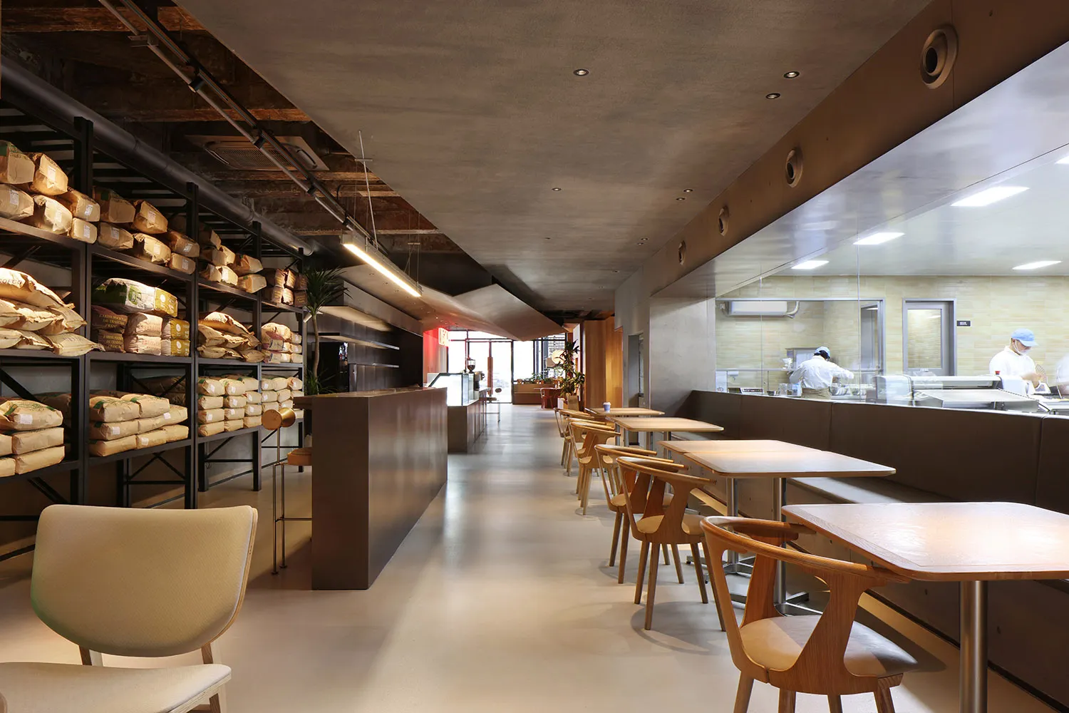 寬敞的工業風餐廳室內,鋪設混凝土地板,搭配木質家具與開放式座位區。