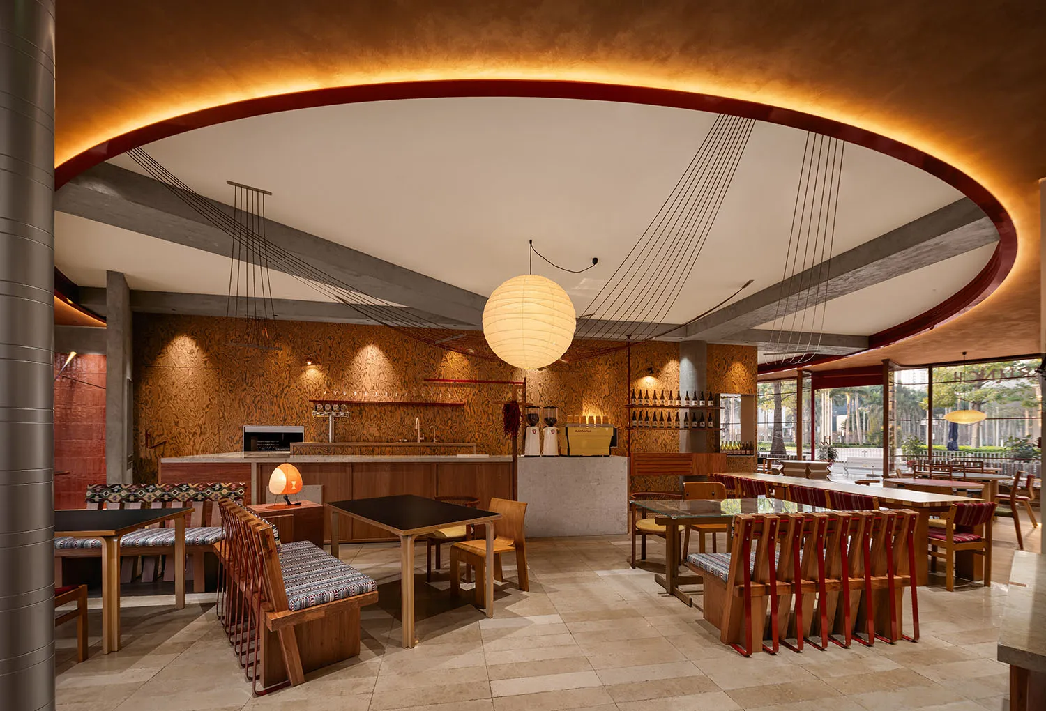 Industrial design restaurant bar with wooden tables and chairs, exposed concrete ceiling beams, and warm lighting.