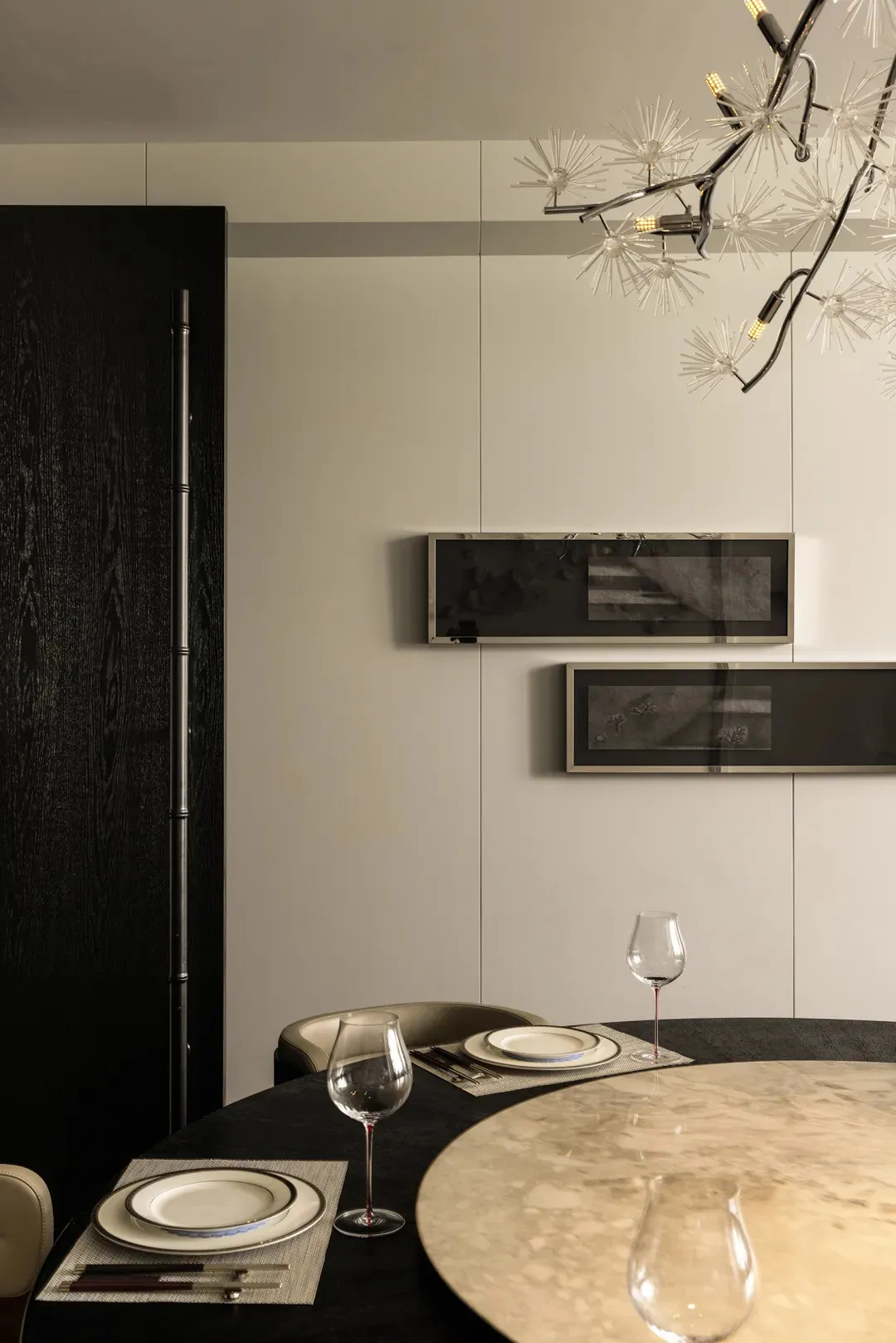 Modern dining room with black paneled wall, metallic artwork, and mother-of-pearl marble table.