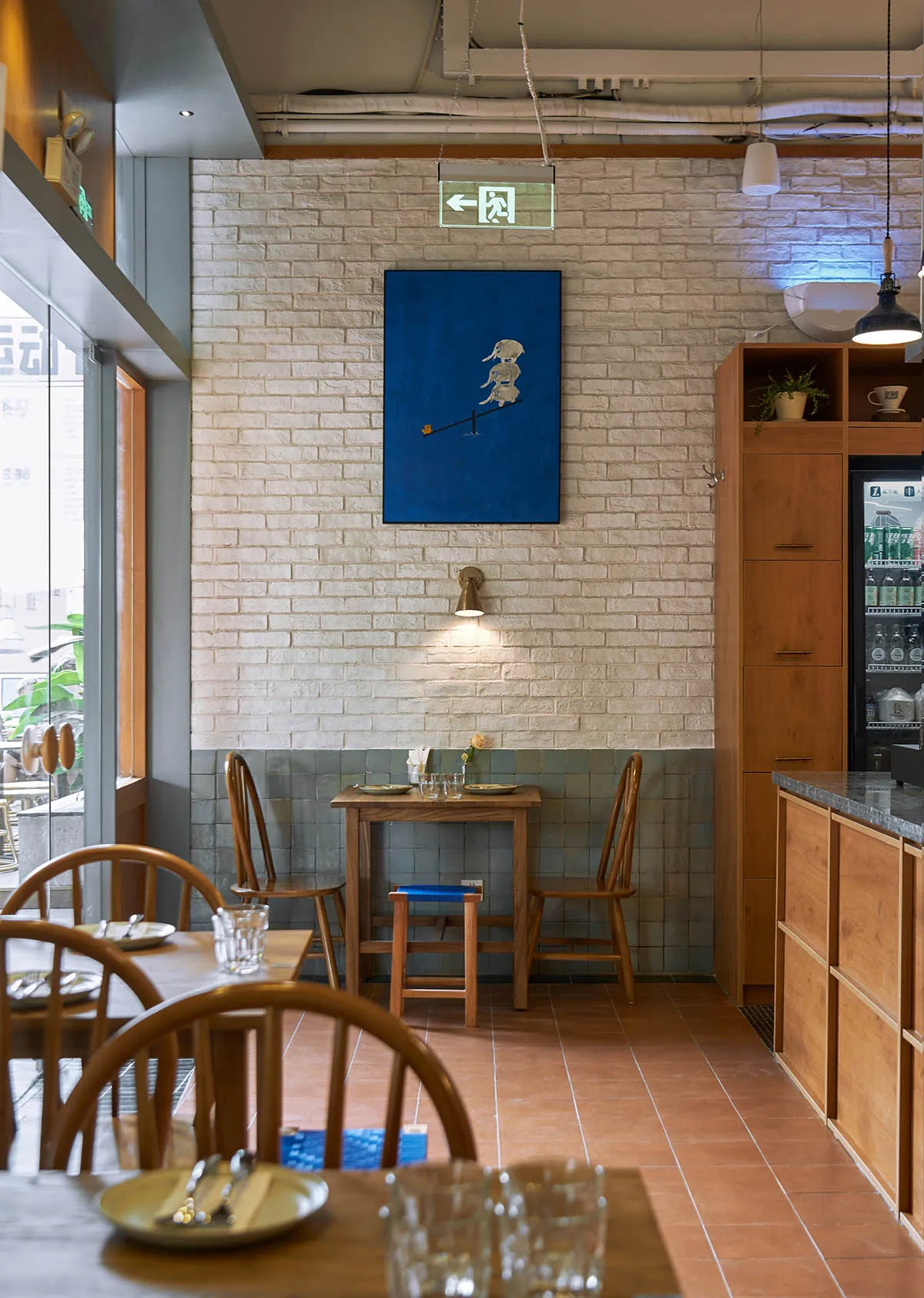 A cozy cafe interior with brick walls, wooden furniture, and tiled seating area.
