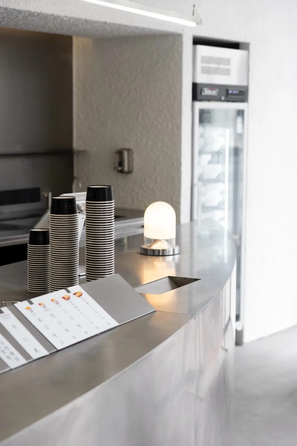 Stacked disposable coffee cups on a sleek metallic coffee counter.