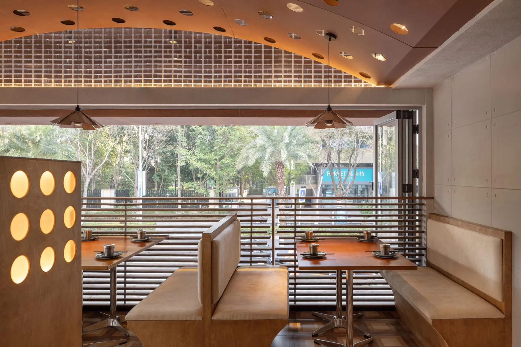 A modern restaurant interior featuring wooden tables, metallic lighting, and a seamless blend of materials.