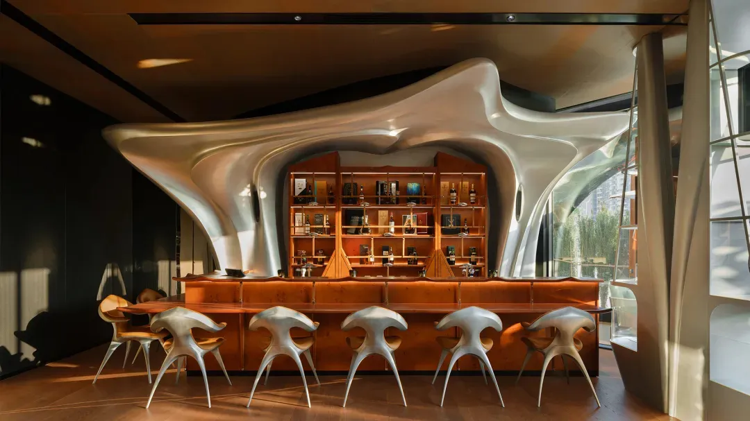 A modern bar with a futuristic, flowing counter and metallic stools.