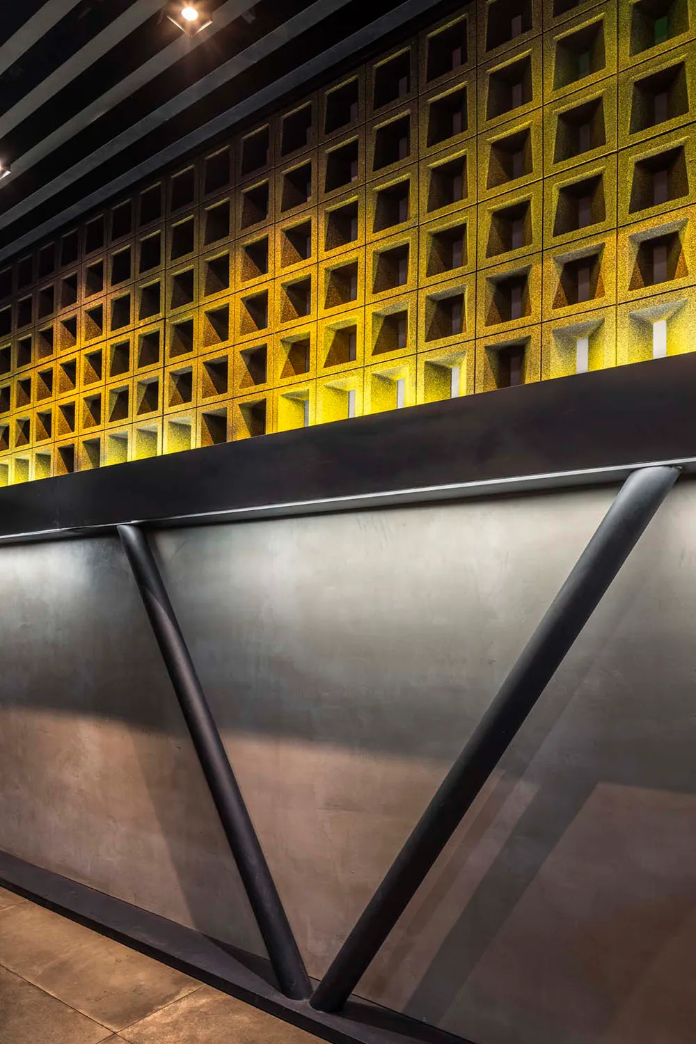 Modern bar counter with metallic structure, recessed lighting, and concrete surface