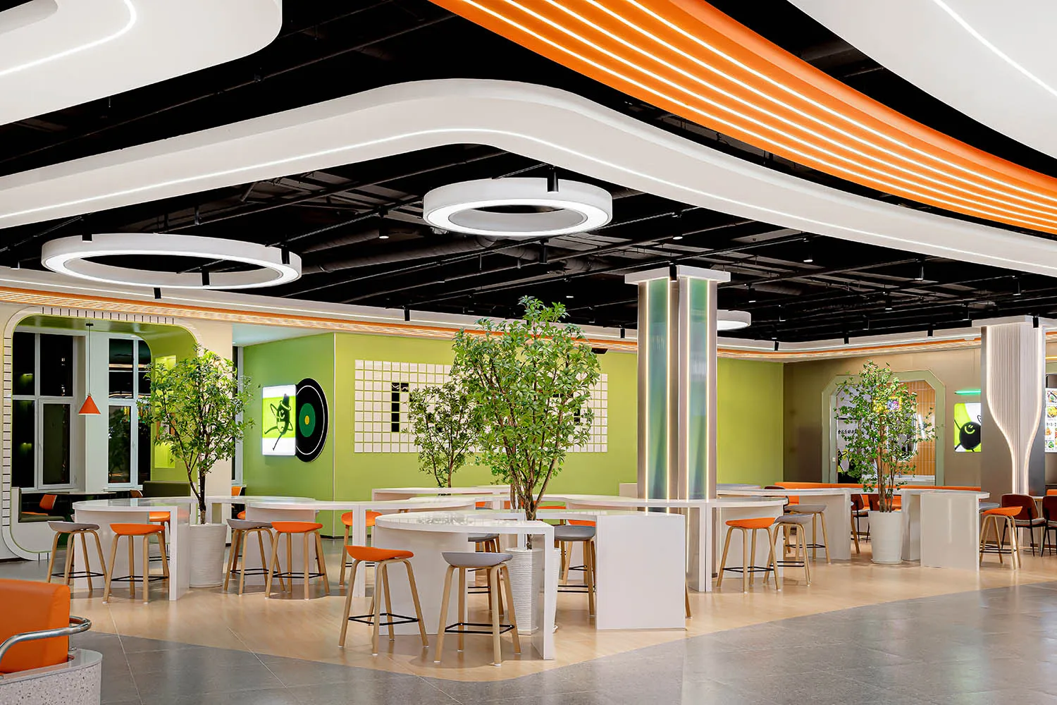 A modern restaurant interior with neon lights, green walls, and white tables