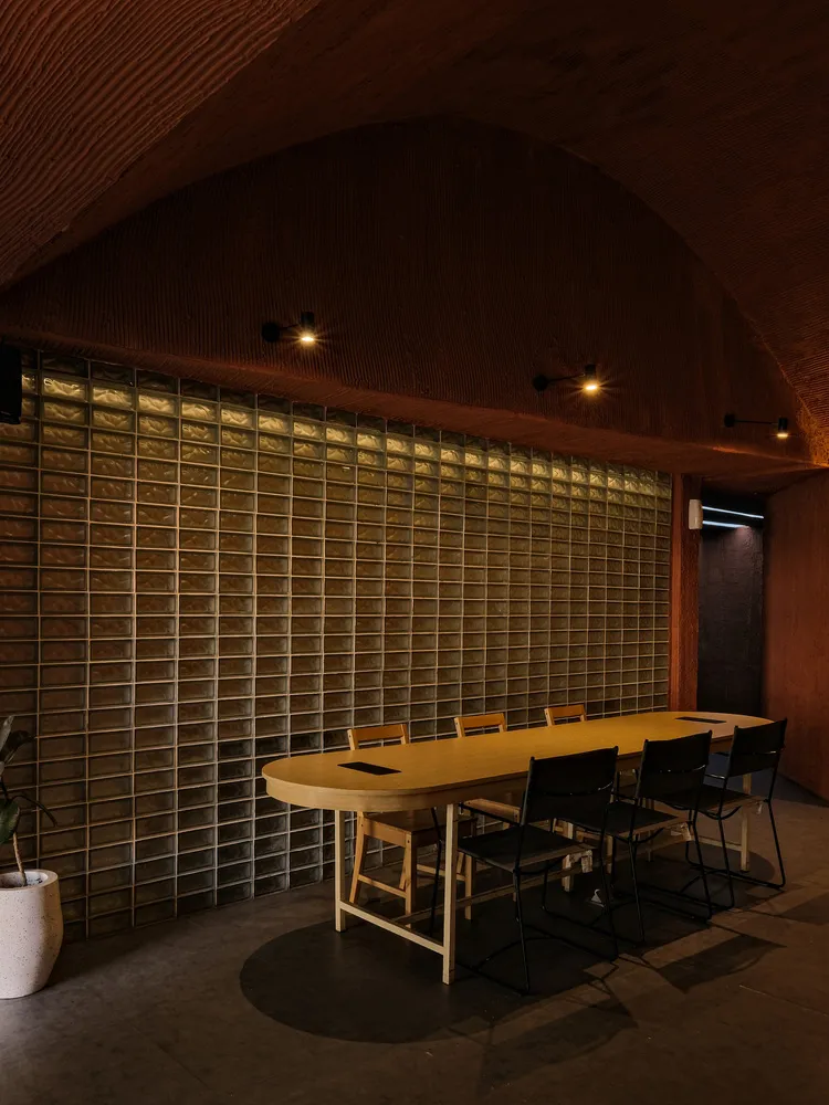 A modern conference room featuring ceramic-tile walls and a wooden dining table with black chairs.