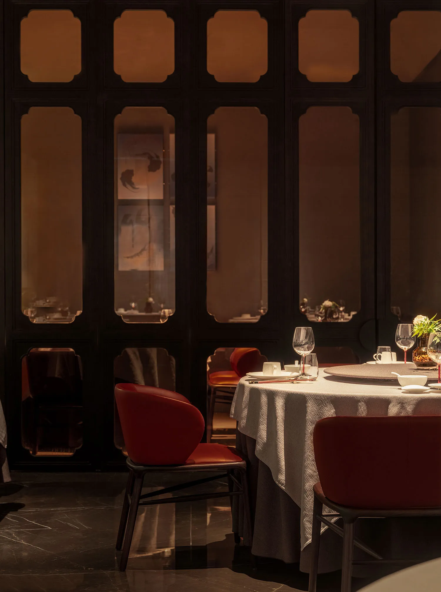 Modern restaurant interior with red leather chairs and round dining table.
