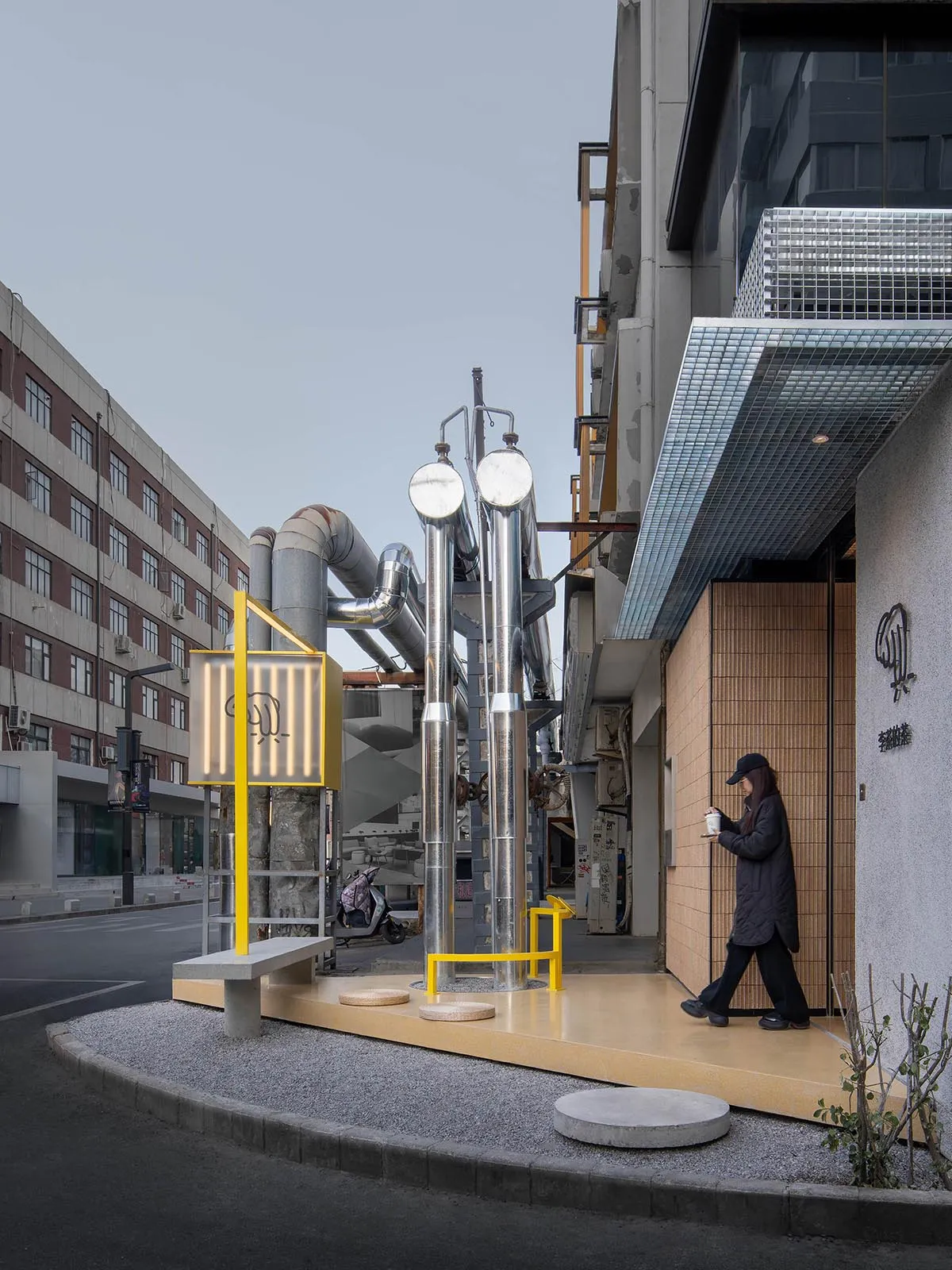 Urban industrial storefront with metallic pipes, glass panels, and wooden accents.