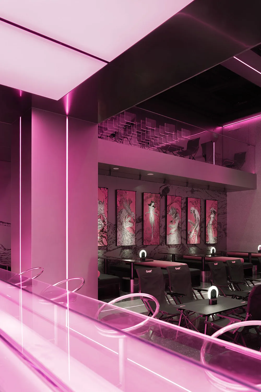 Industrial-style restaurant interior featuring metal tables, glass railings, and pink lighting