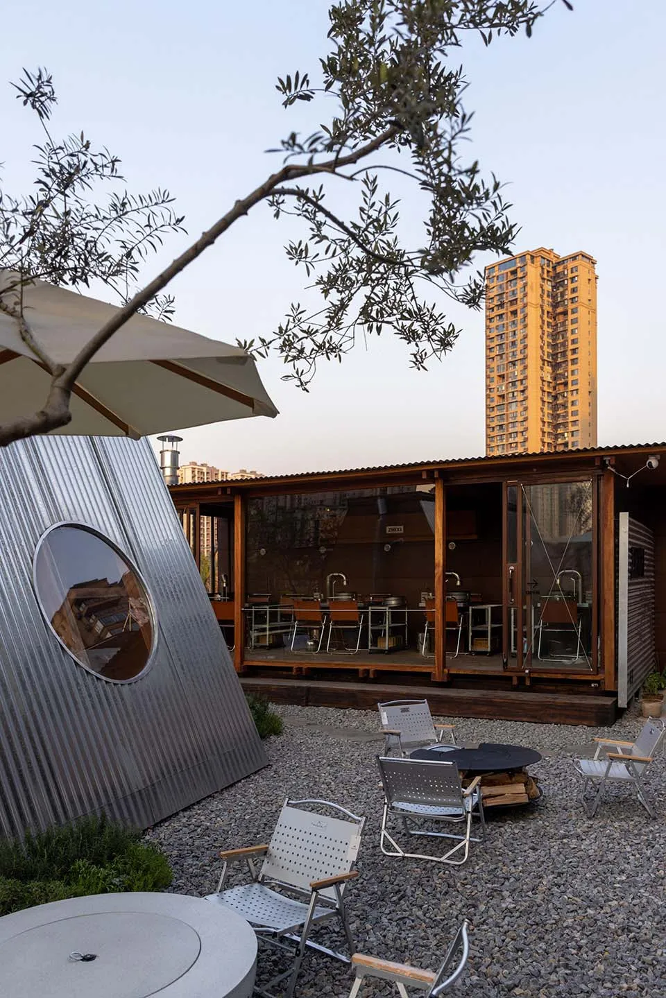 A minimalist outdoor café featuring metal, wood, and stone materials.