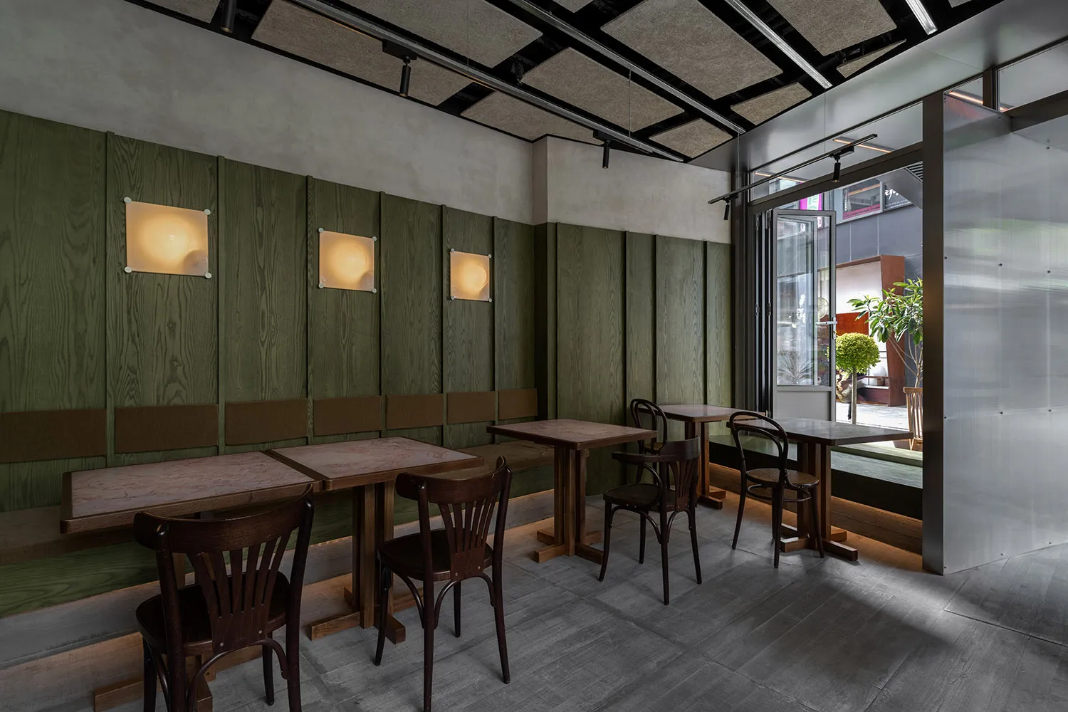 Industrial restaurant interior with green wooden walls, wooden tables, and chairs.