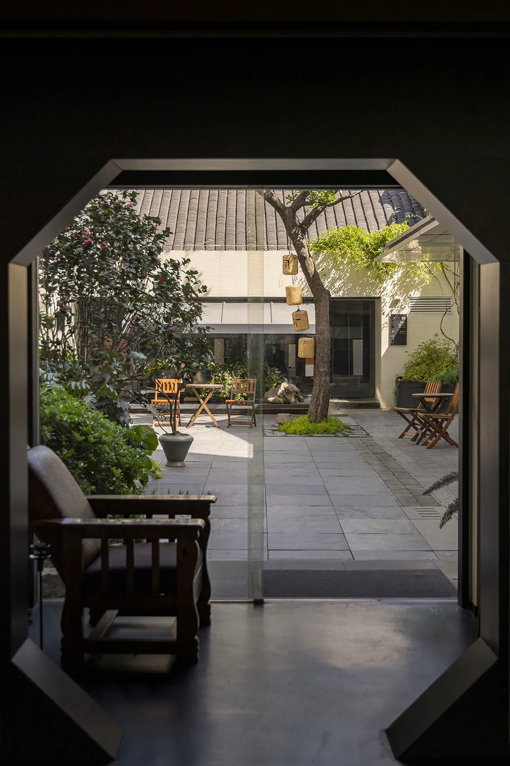 Modern residential entryway featuring wooden furniture, glass lanterns, stone tiles, and bamboo decor.