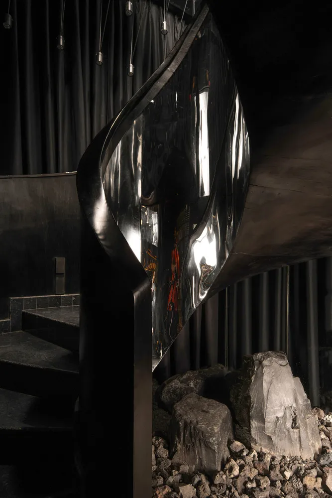 A modern industrial staircase featuring metal railings, stone steps, and concrete elements.