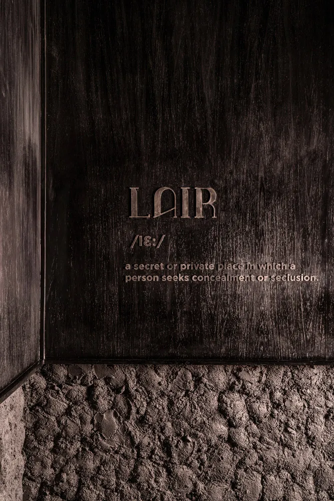 特寫深色牆面室內,呈現木質紋理,牆上刻有「Lair」字樣。