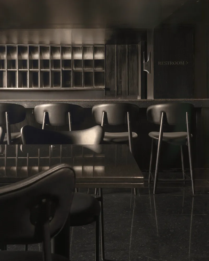 Industrial-themed restaurant interior with metallic counter, leather seating, and glass partitions.