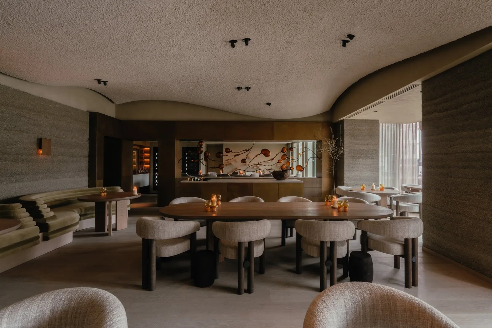 現代餐廳內部,配有木質餐桌、布面座椅,以及金屬吧檯的吧台區域。