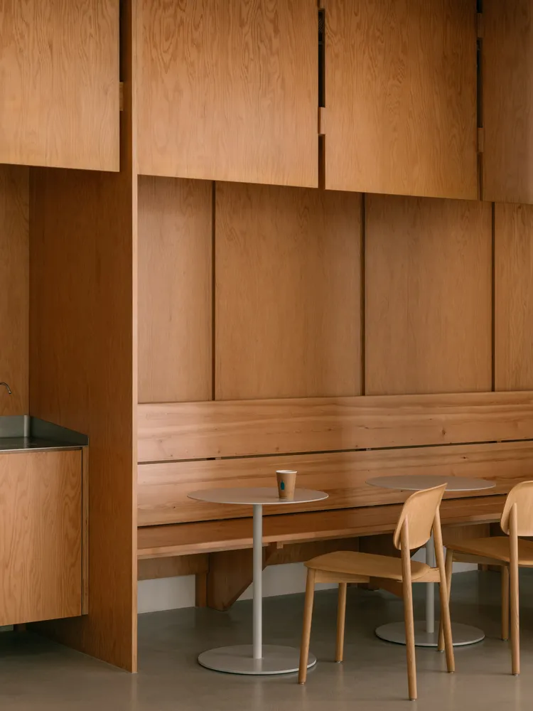 A modern coffee shop with wooden paneling, tables, and chairs.