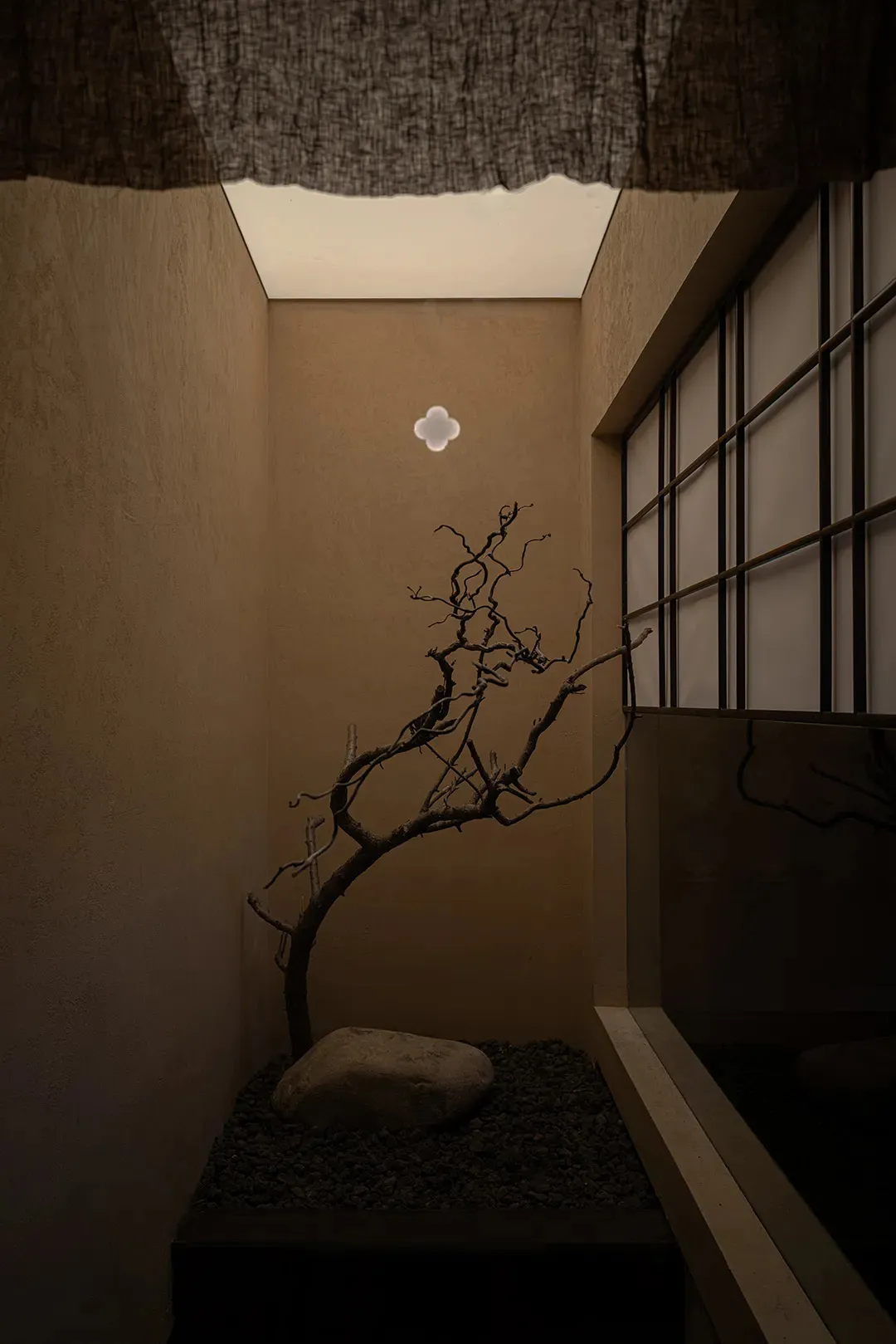 A minimalist corridor featuring concrete walls, stone flooring, and gravel accents.