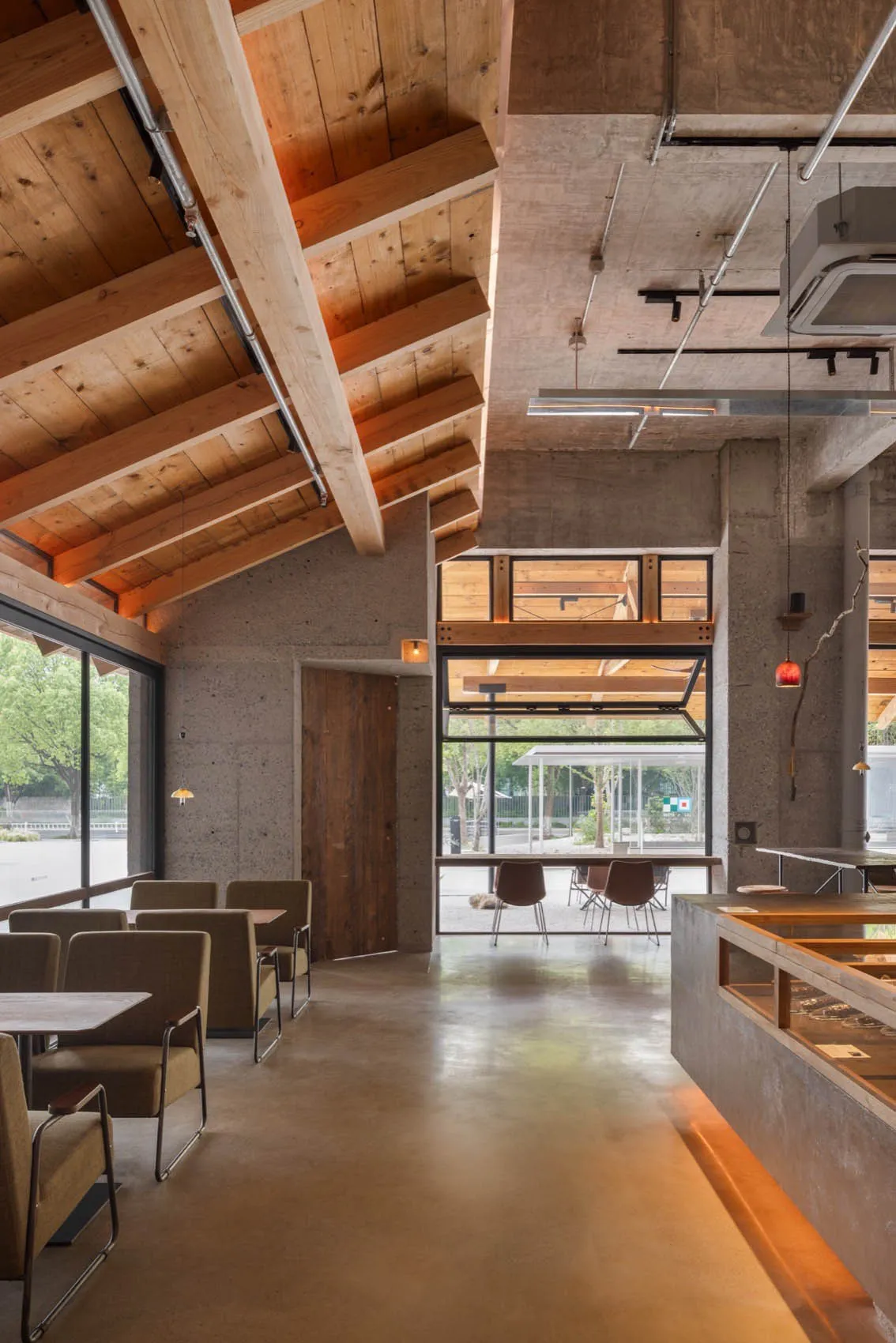 An industrial-style coffee shop interior with concrete walls, wooden elements, and a high ceiling.