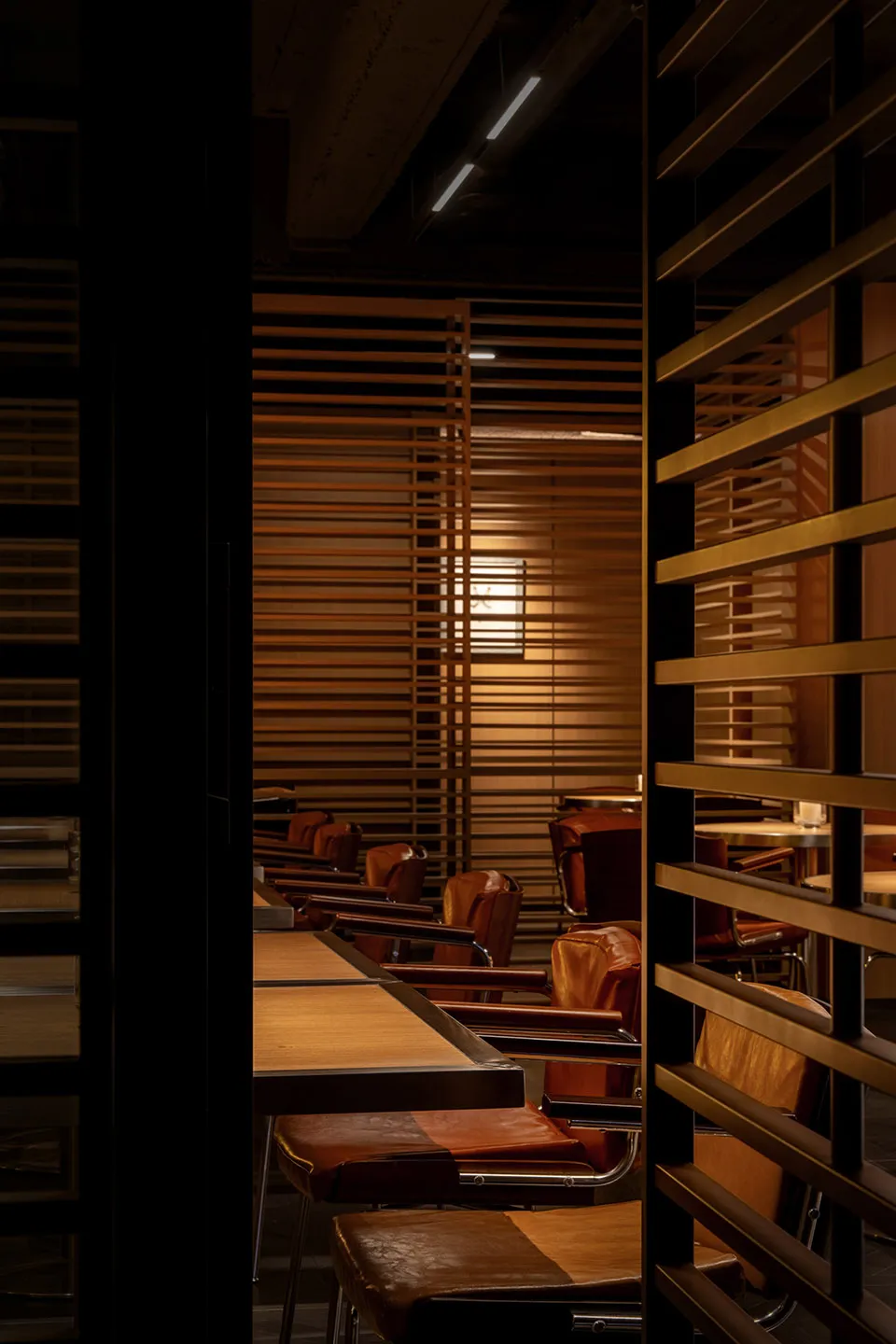 A row of brown leather restaurant seating with wood tables and metal legs.