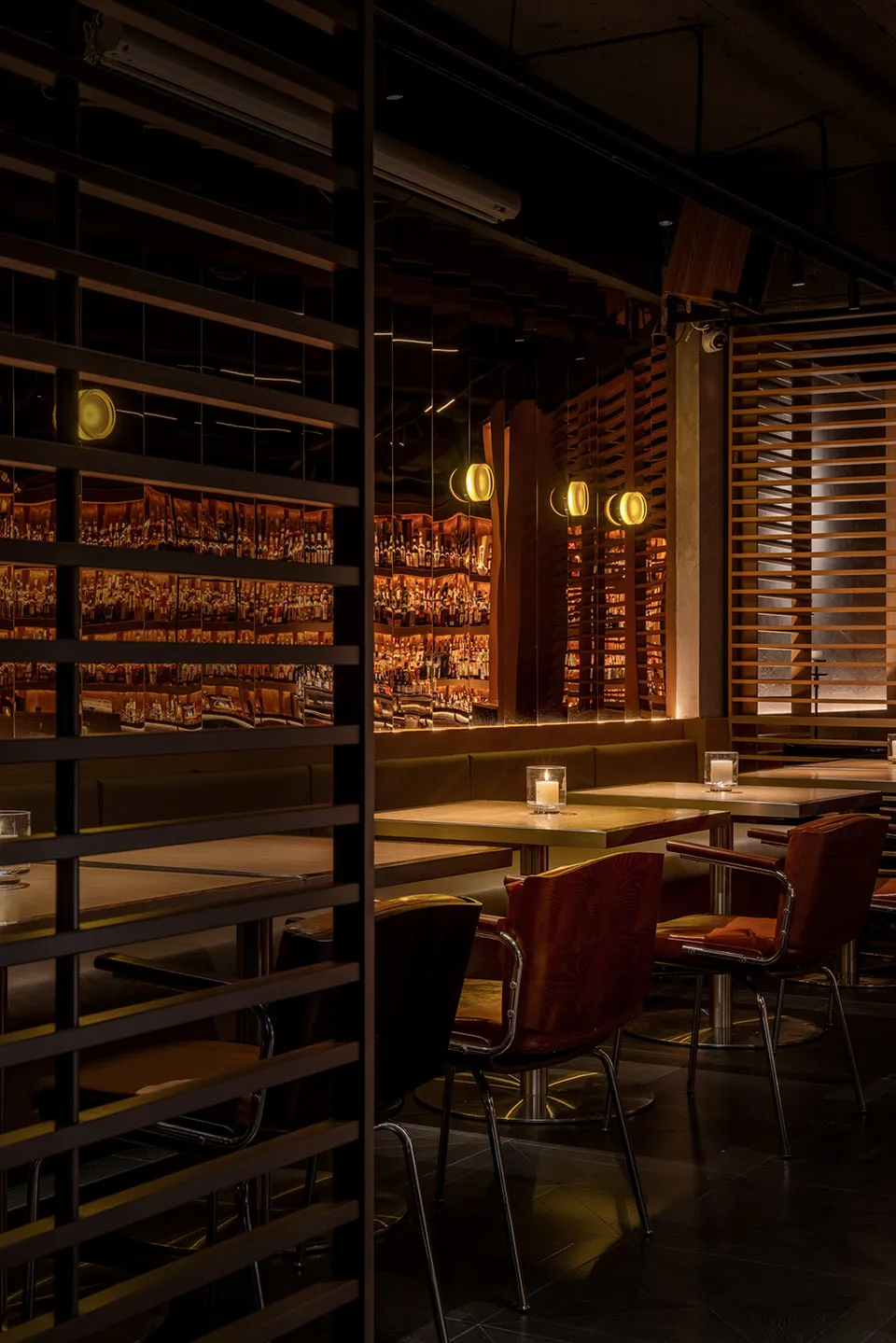 A modern restaurant bar with wooden tables, metal chairs, and a well-stocked back bar.