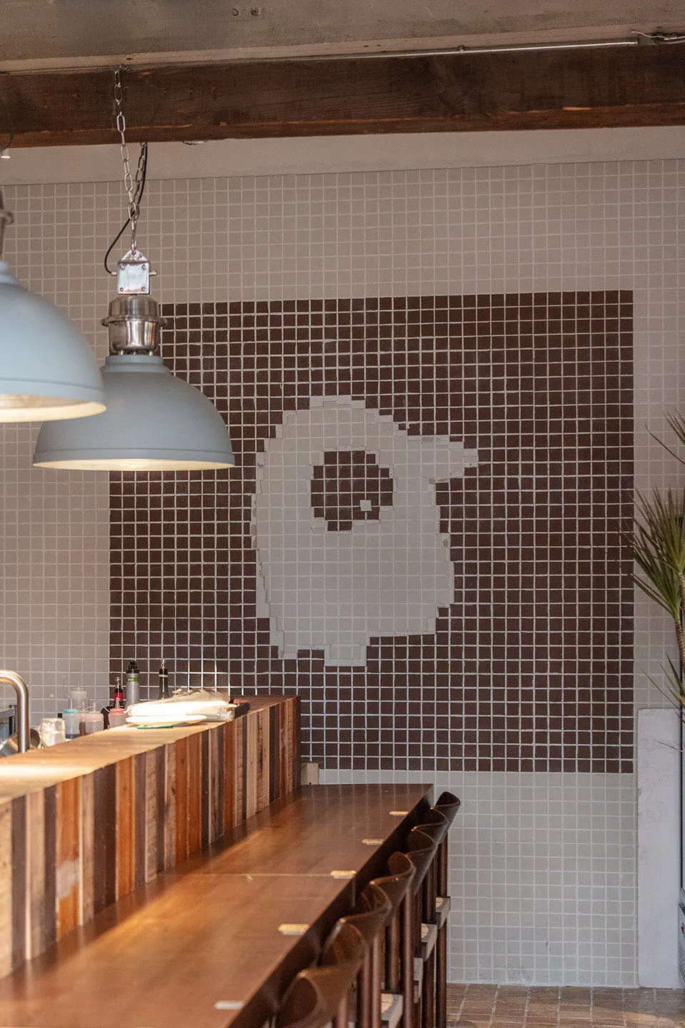 A wooden coffee shop counter featuring tiled walls.