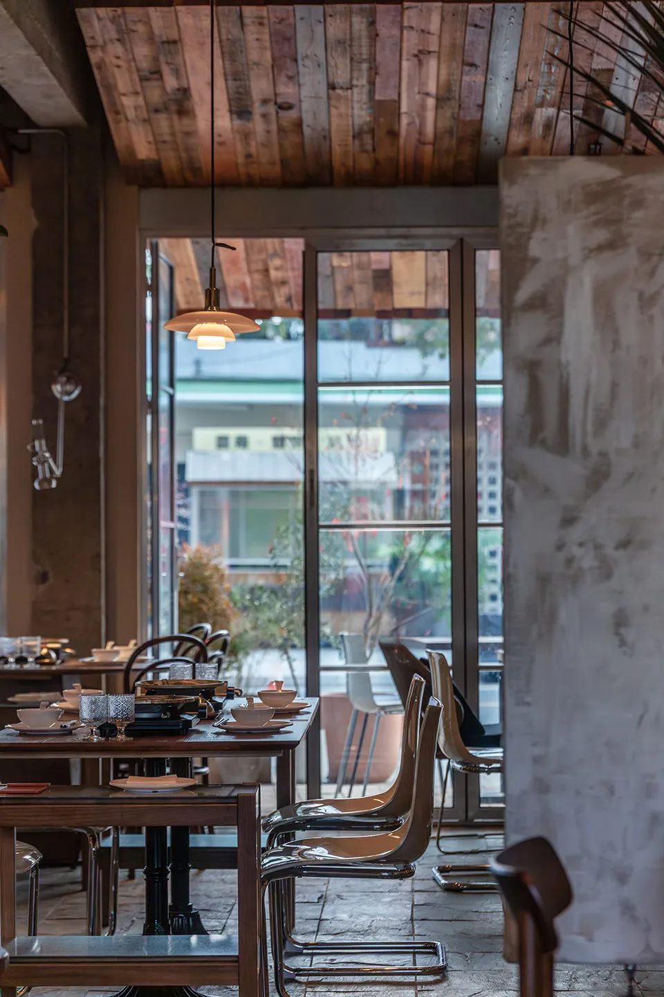 A stylish dining area with wooden furniture and large windows, offering a cozy and contemporary atmosphere.