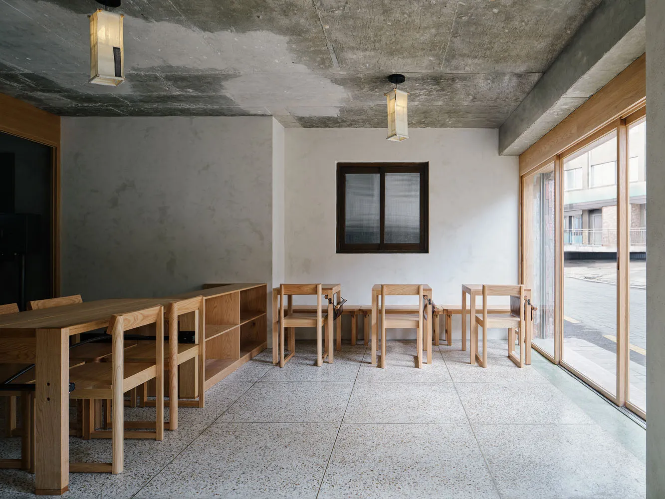 Empty wooden restaurant seating area with concrete flooring and concrete ceiling.
