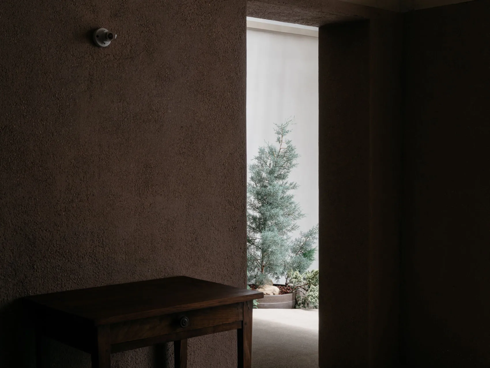 A minimalist interior with concrete walls and a wooden table.