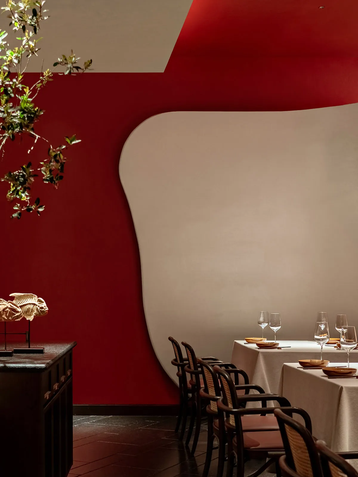 A modern restaurant interior with red velvet walls and white furniture.