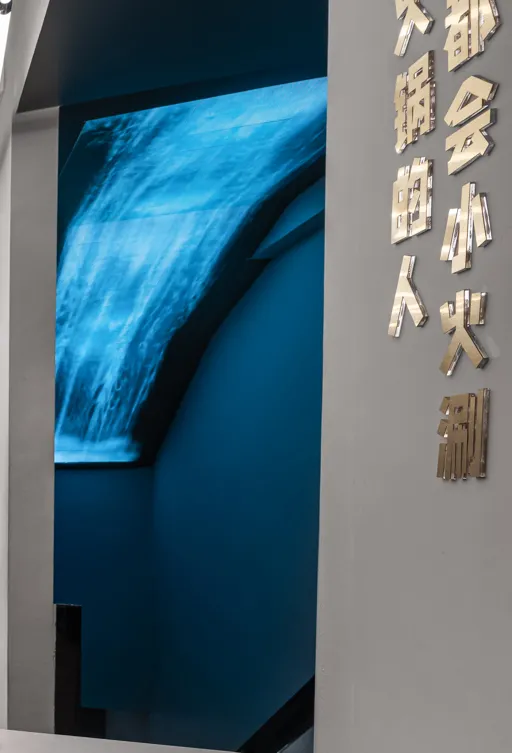 A modern architectural installation featuring a waterfall and illuminated lighting elements.