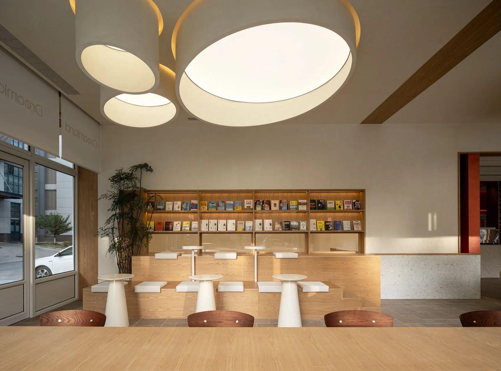 現代簡約咖啡廳室內,搭配木質餐桌、吧台椅,以及圓形玻璃餐桌。