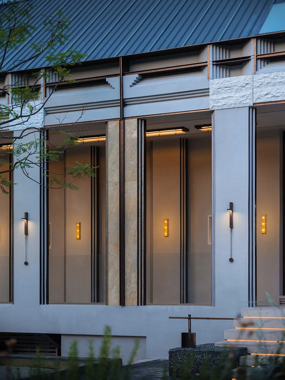 Modern residential entryway featuring a concrete facade and contemporary lighting fixtures.