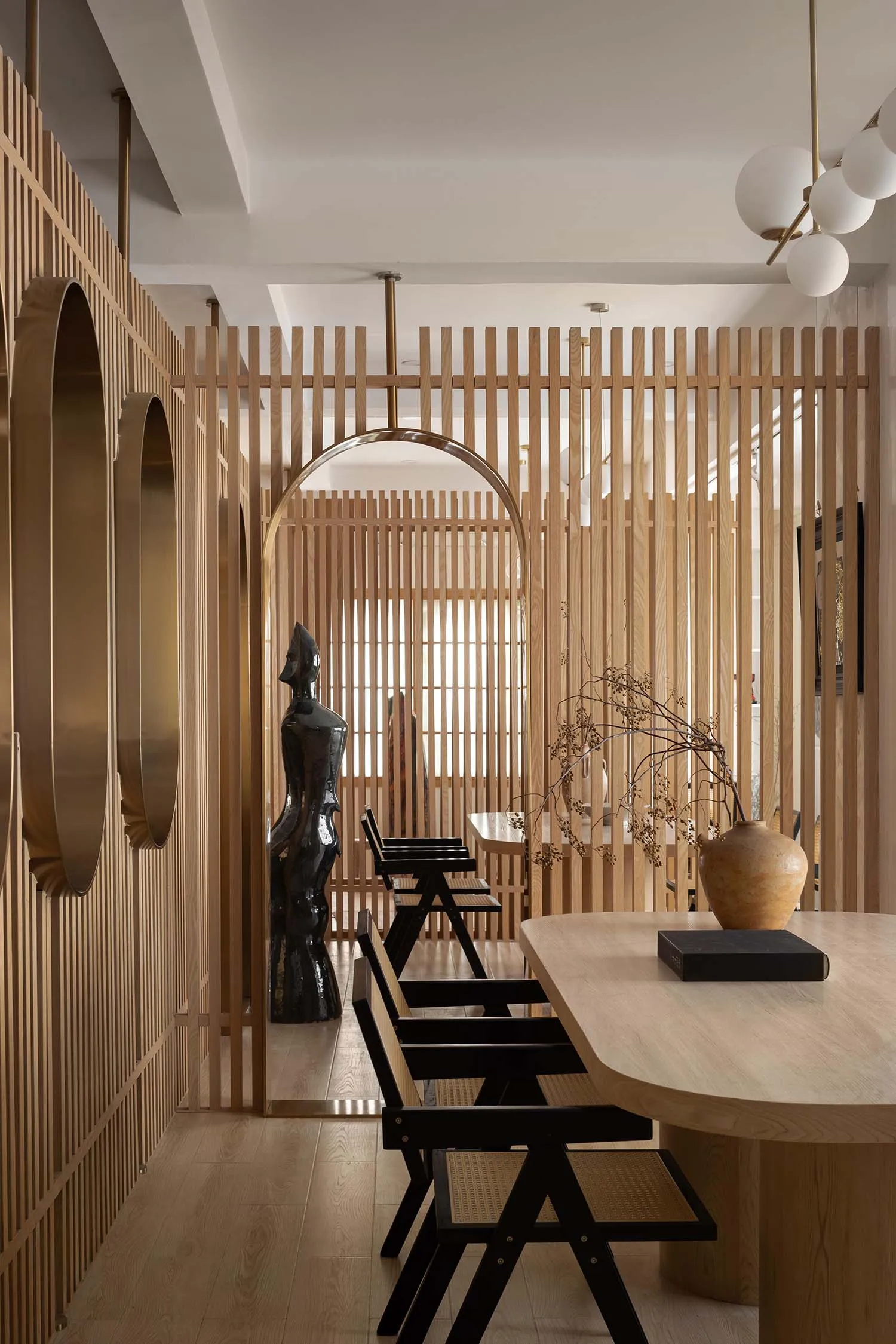 Modern dining room with wooden furniture, black chairs, and a wooden table.