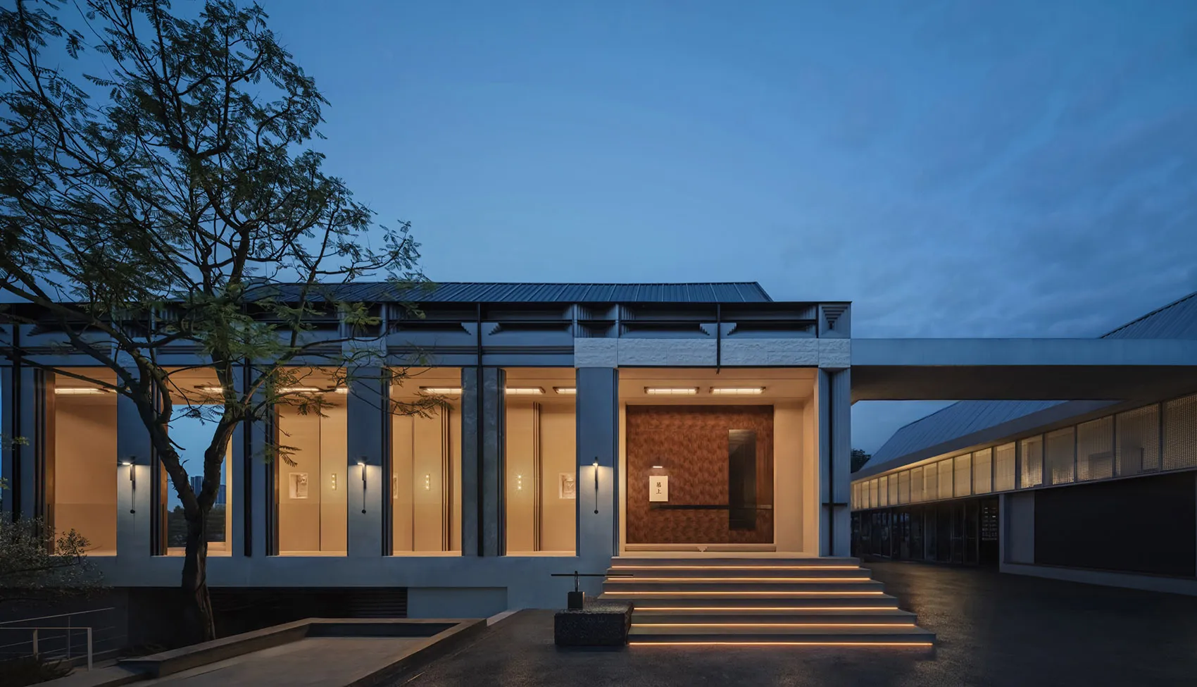 A modern building with a concrete exterior illuminated at night.