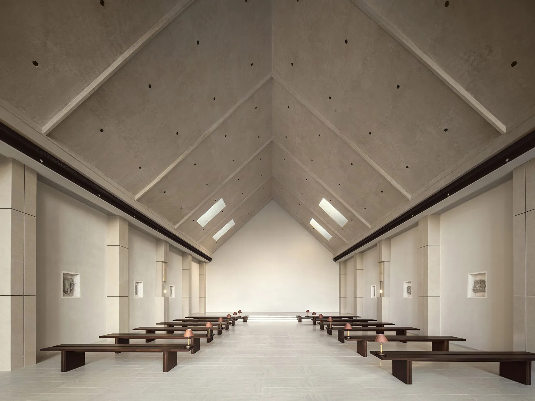 A minimalist, modern church interior with concrete walls and floors, high ceiling, and natural light.