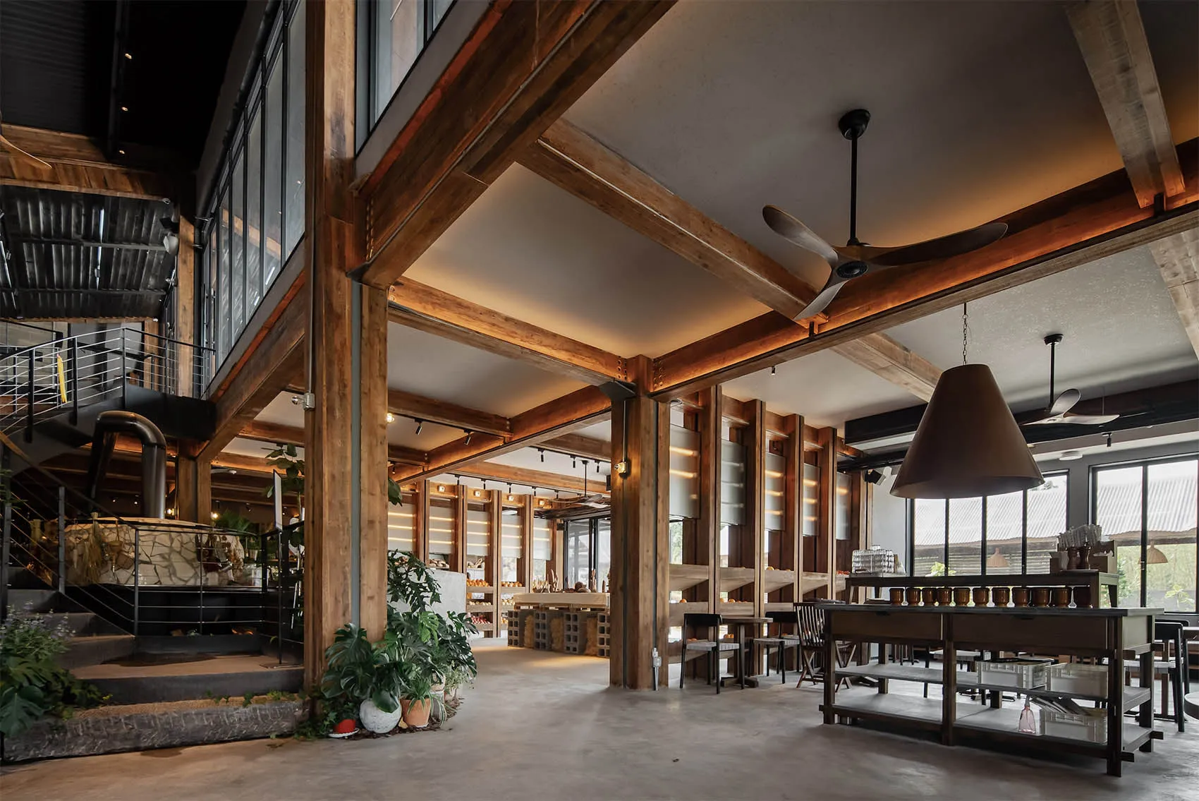 Industrial-style restaurant interior with wooden beams, concrete flooring, and metal accents.