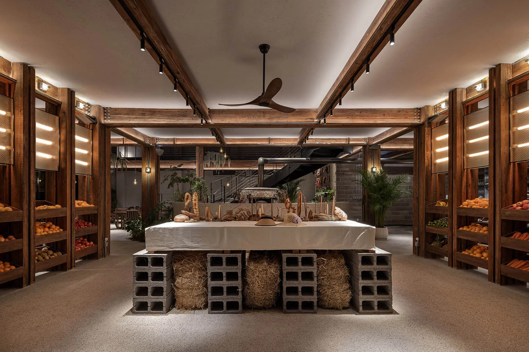 Industrial-style restaurant interior with wooden structures, concrete elements, and hay accents.