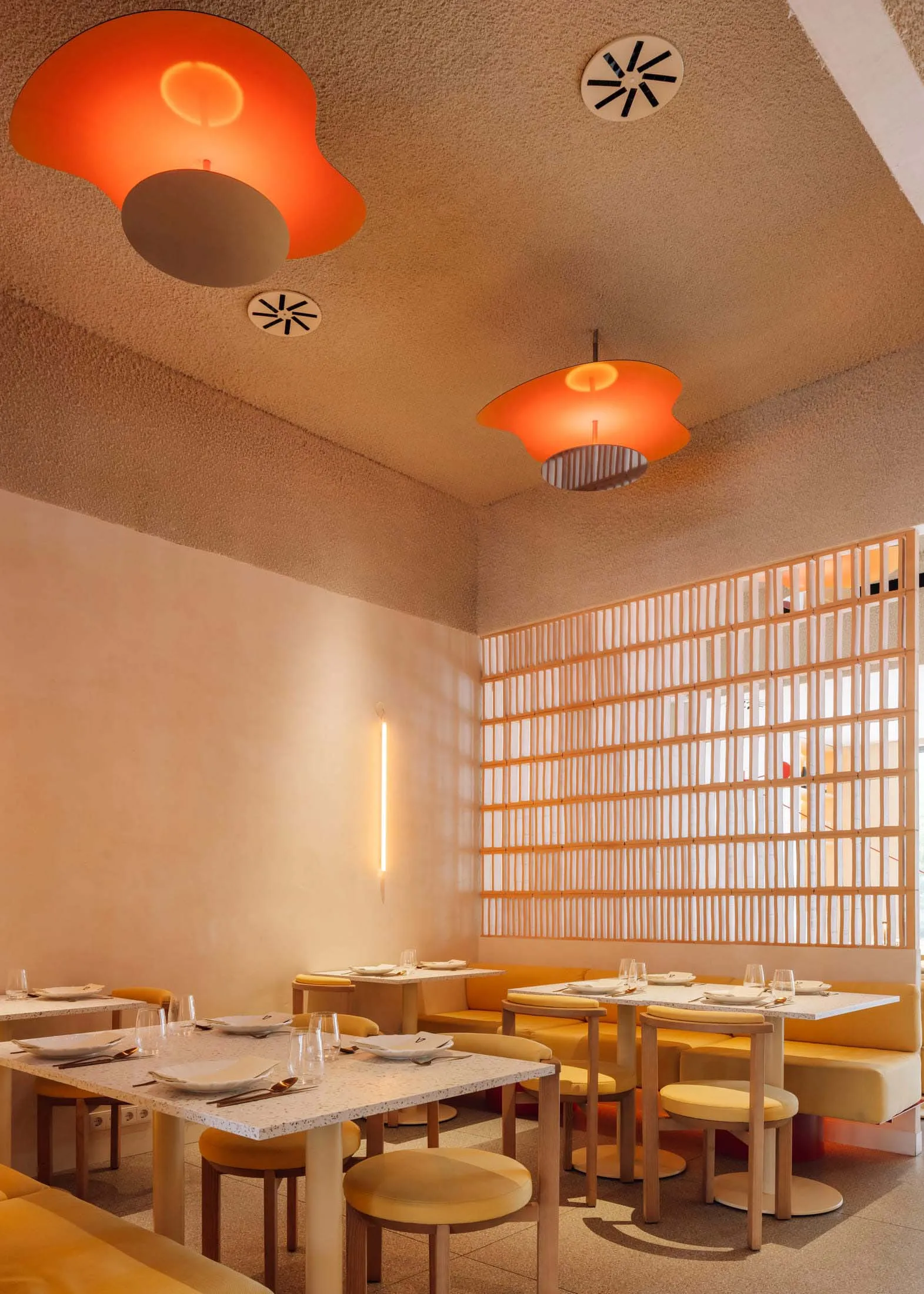 A minimalist restaurant interior with terrazzo flooring and ceiling lights.