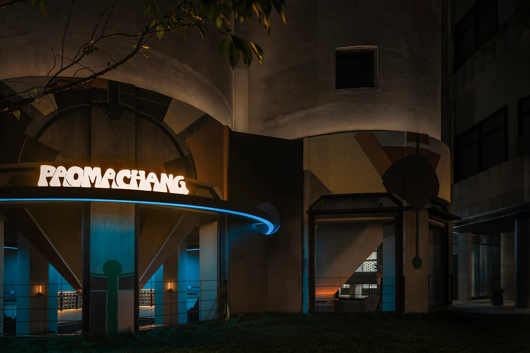 An illuminated, modern-industrial storefront with a concrete exterior and warm lighting features.