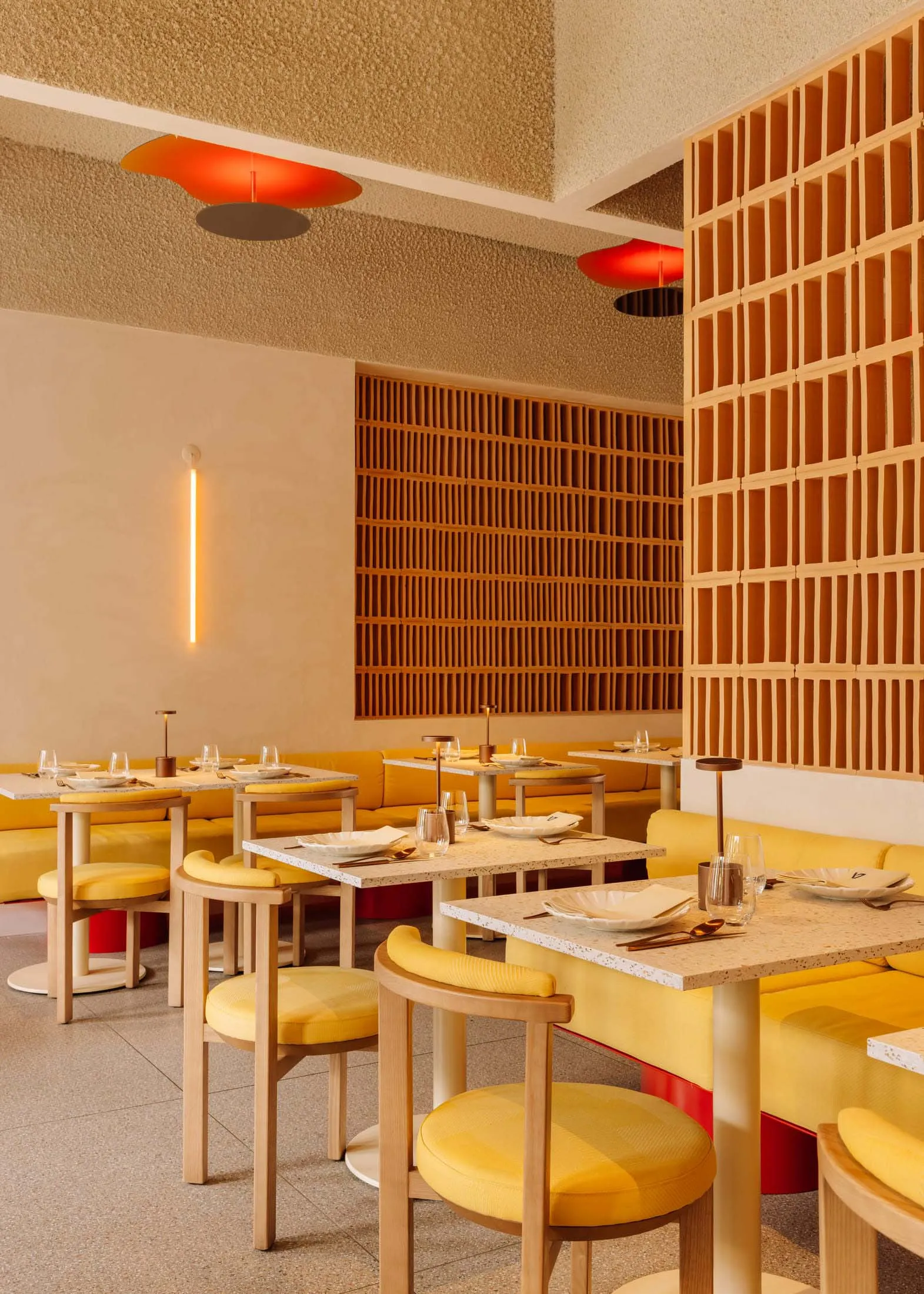 Modern restaurant interior with yellow seating, concrete walls, and wooden accents