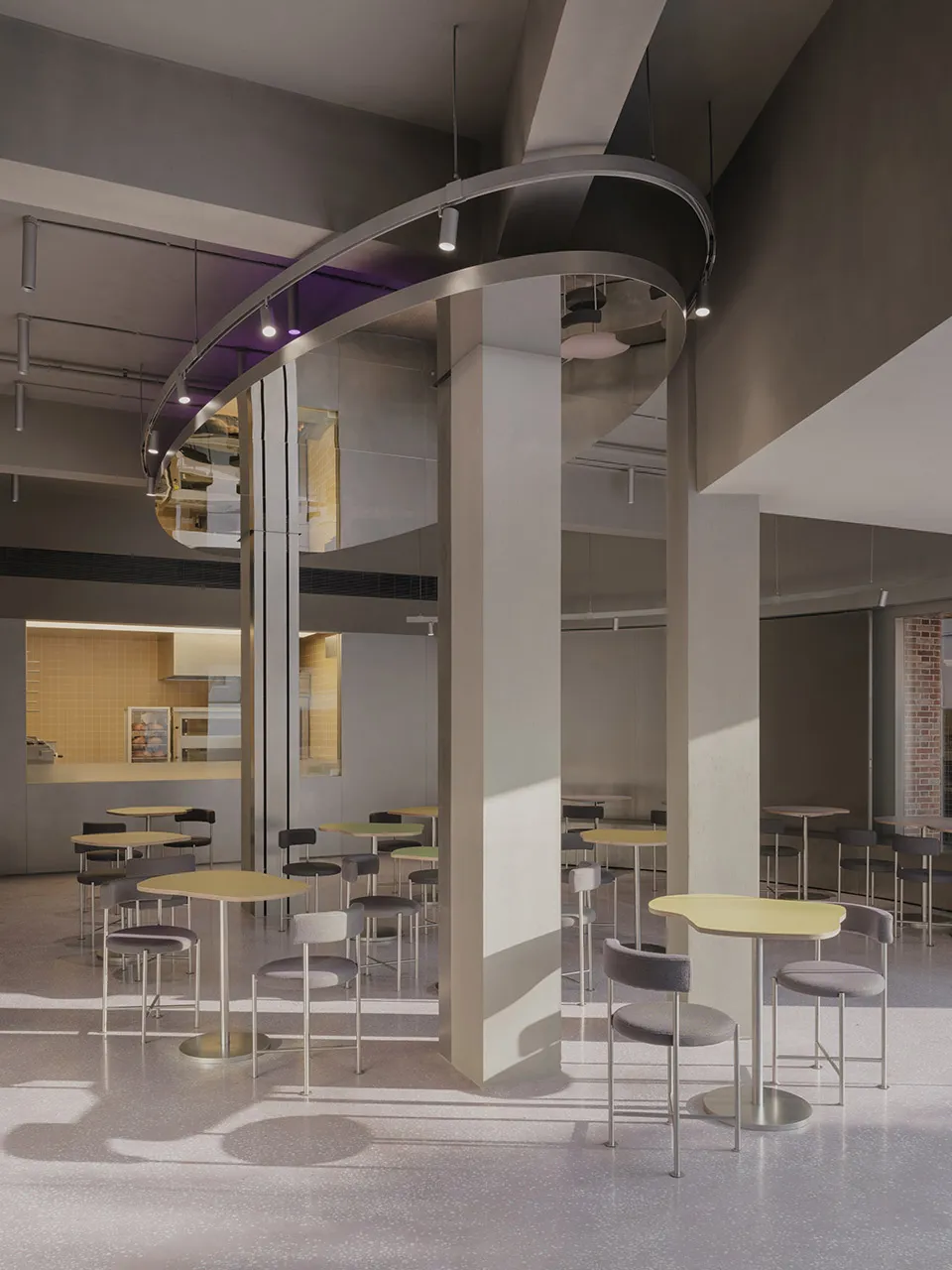 A spacious, industrial-style restaurant interior featuring concrete flooring, high ceilings, and modern lighting fixtures.