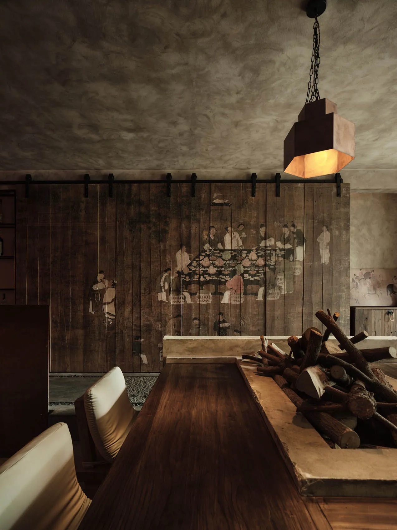 A cozy restaurant interior with rustic wooden walls, a fire pit, and traditional Chinese painting