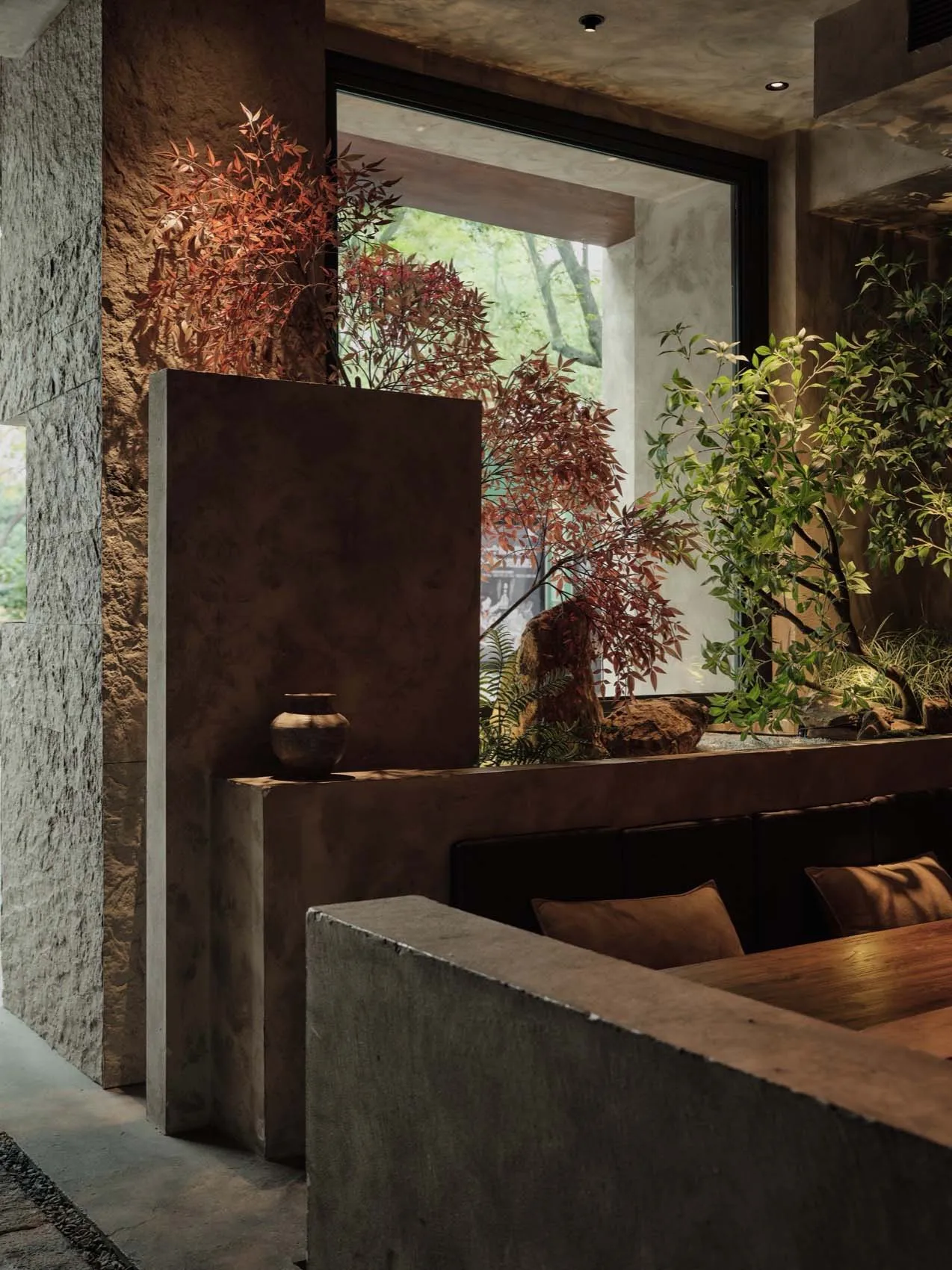 Interior of a minimalist restaurant with concrete walls, seating area, and plants.
