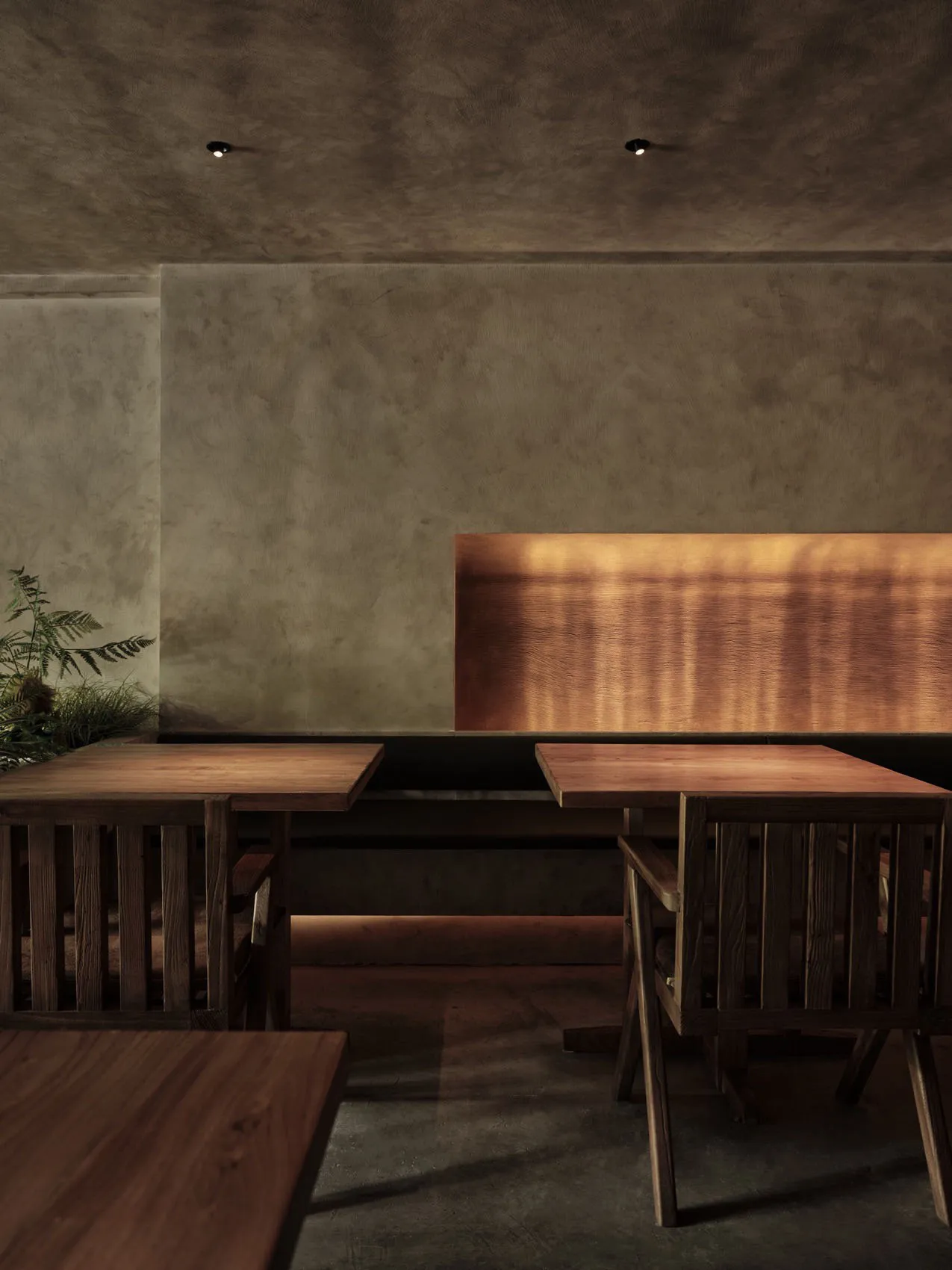 A modern restaurant interior featuring a combination of concrete and wooden elements with warm lighting.