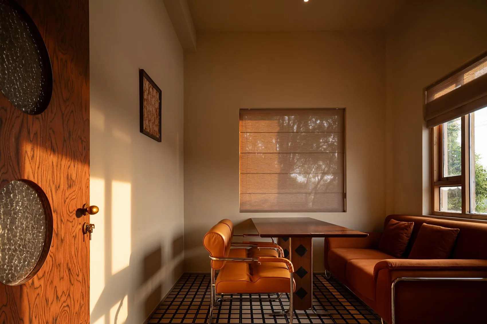 A cozy indoor living room featuring orange upholstered furniture, a wooden table, and a large window with natural light.